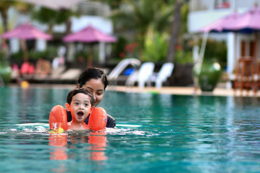 Kid with mom swimming in the pool on some of the Krabi resort in Thailand