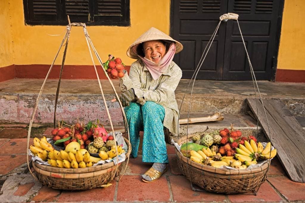 Vietnamese woman carrying fruits for sale in Hoi An town, Vietnam