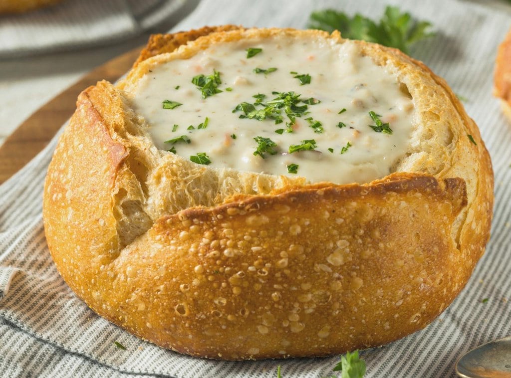 A serving of clam chowder in a bread bowl
