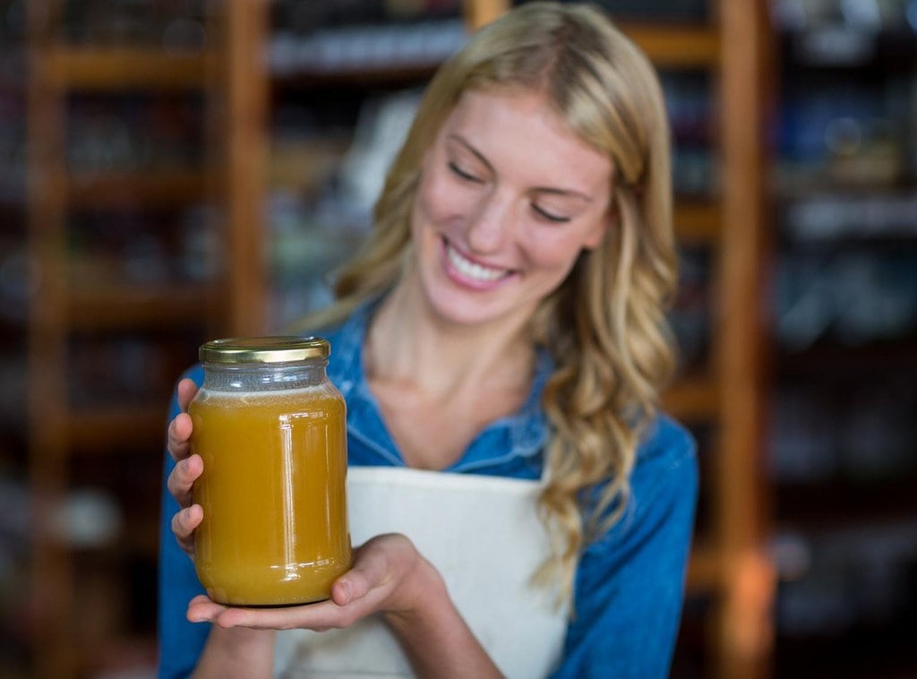A woman holding up a jar of honey