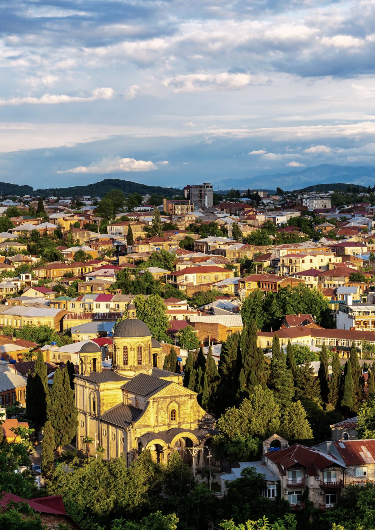 Cityscape of Kutaisi, Georgia with Bagrati Cathedral and colorful residential buildings and houses during sunset