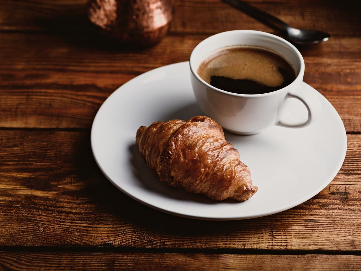 A cup of coffee and a croissant