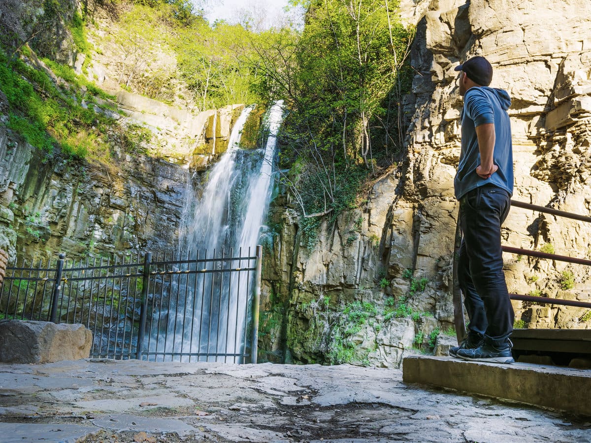 A tourist admiring the Leghvtakhevi Waterfall in Tbilisi, Georgia