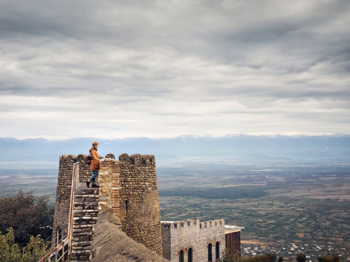A tourist at a fortress tower wall with view to the mountains in Sighnaghi, Georgia