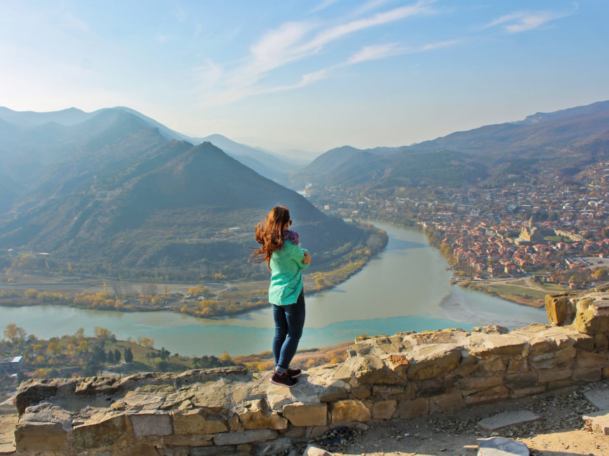 A tourist standing on a stone wall at the Jvari Monastery in Mtskheta, Georgia