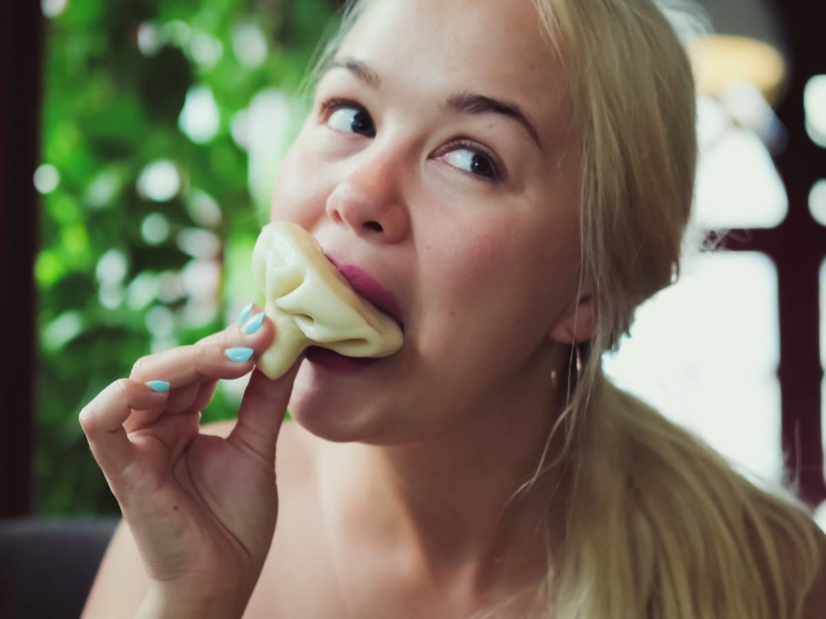 A woman eats hot khinkali at a restauran in Georgia