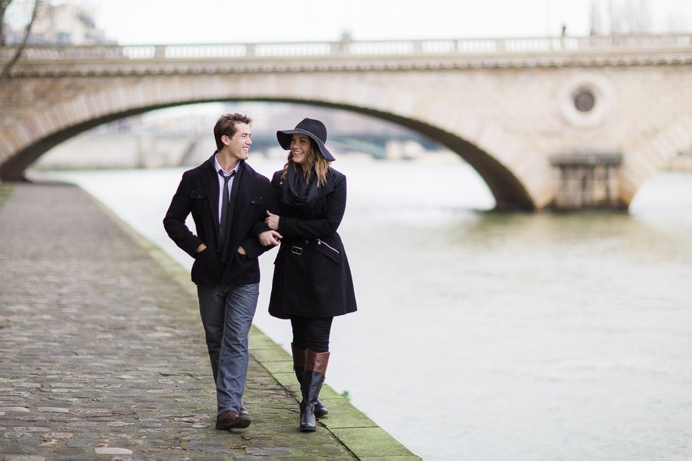 A couple walking by The Seine in Paris during winter
