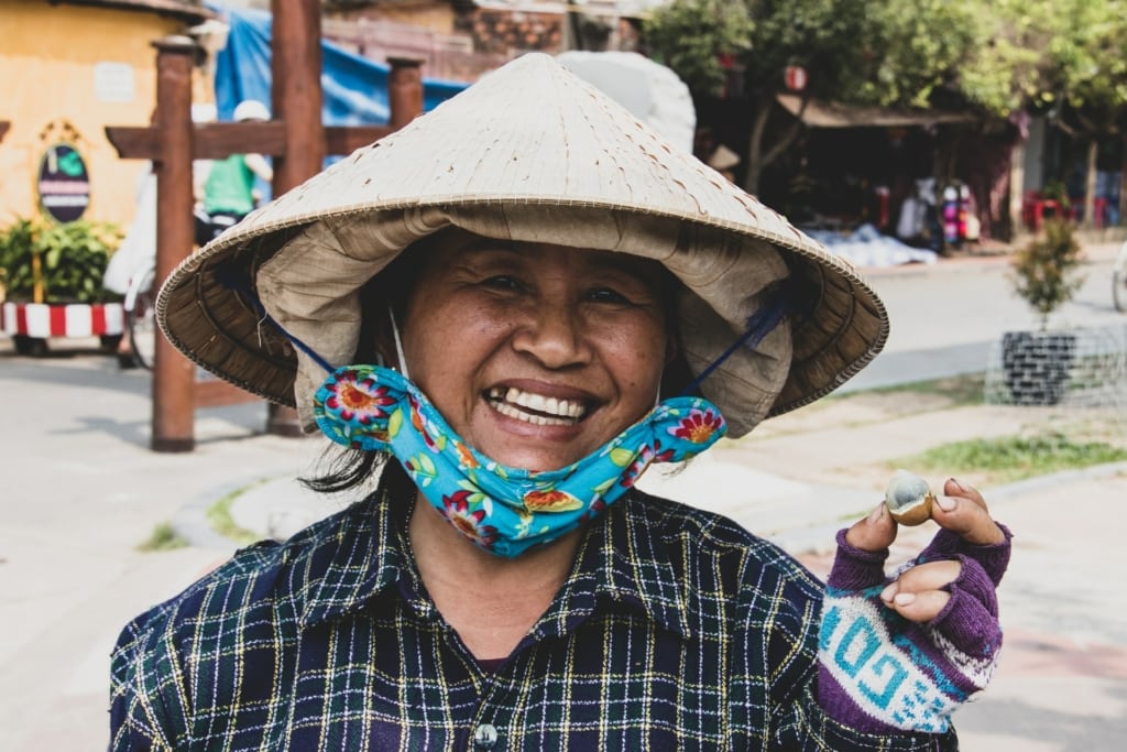 A smiling women wearing a conical hat in Vietnam