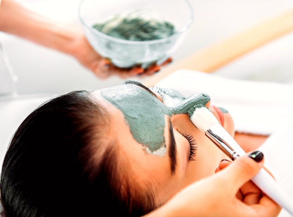 A woman getting a clay mask facial treatment